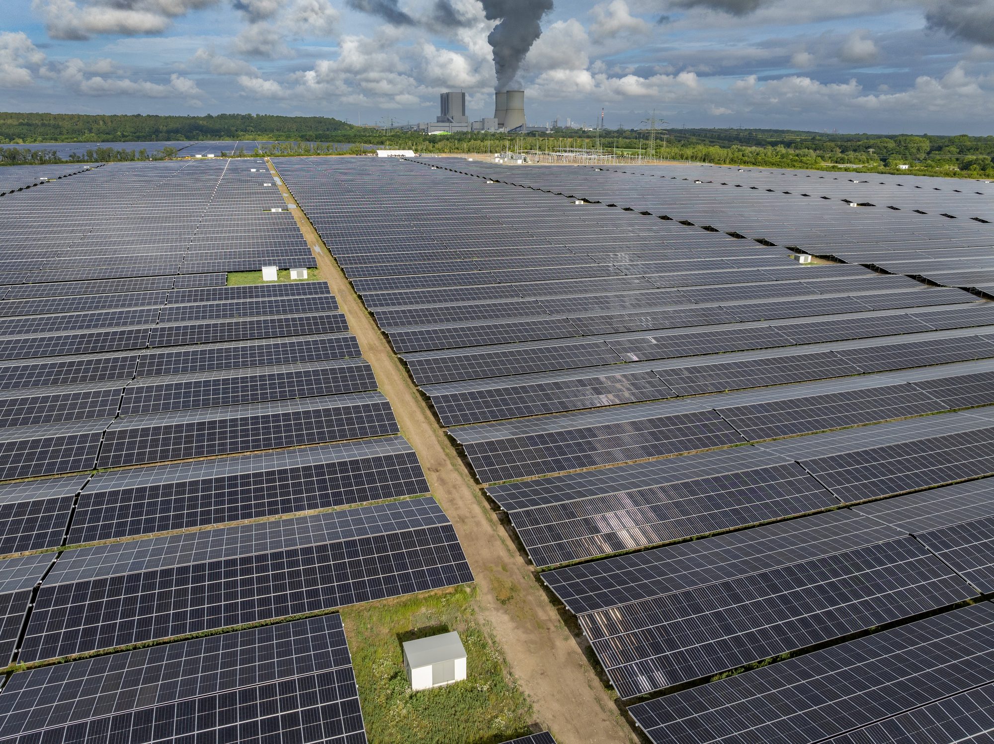Schräge Luftaufnahme von Modulreihen im Solarpark Witznitz mit Wartungsweg und Technikstation